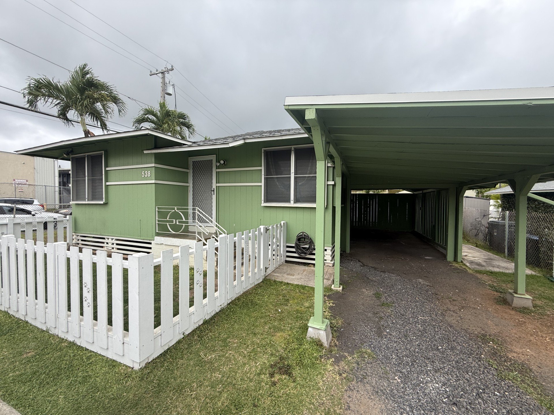 A green house with a white picket fence.